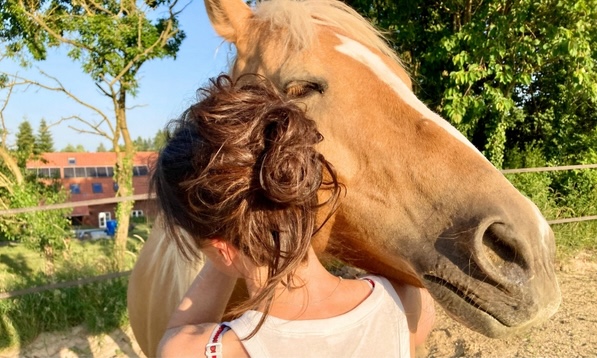 Kati mit Pferd umarmend